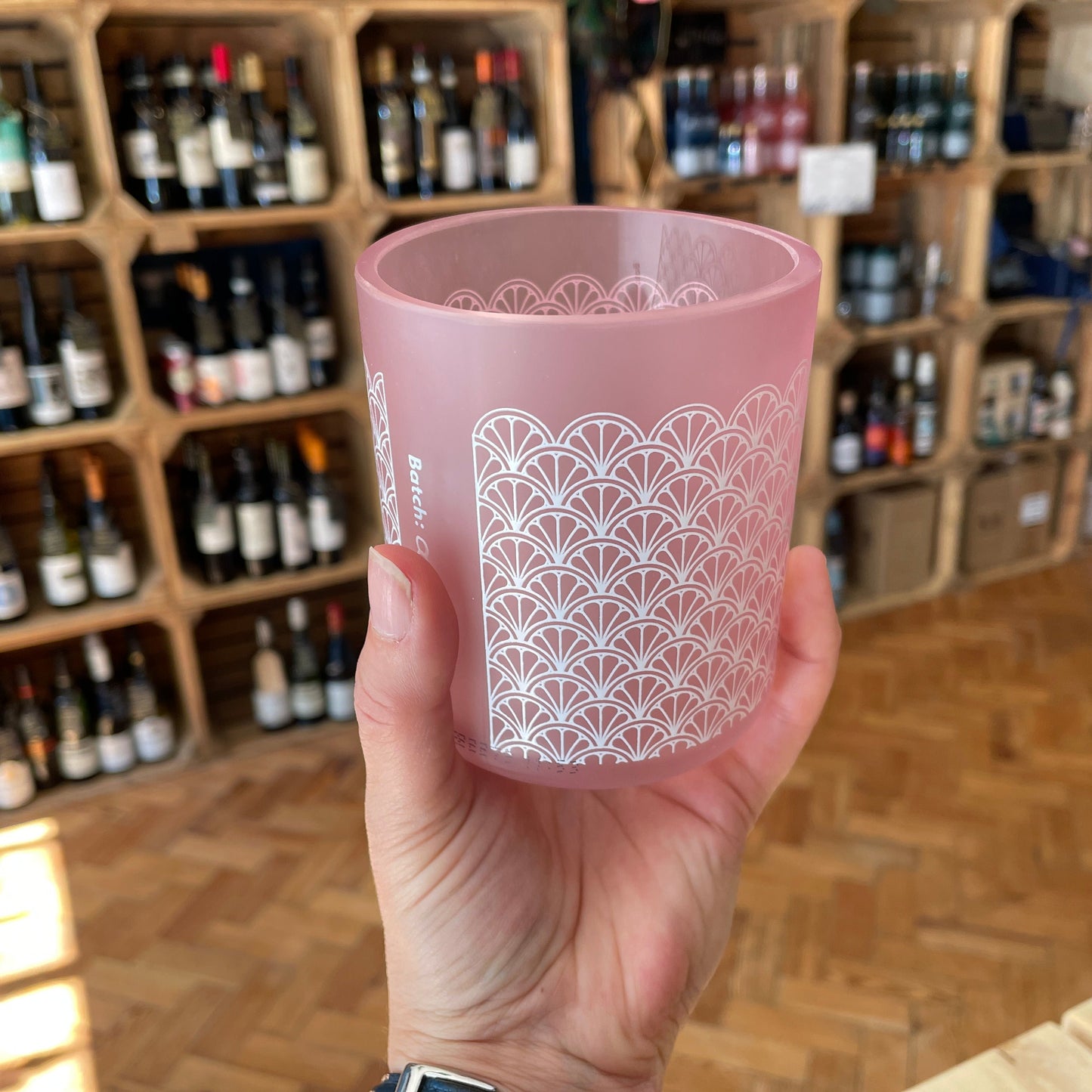 A hand holding an Upcycled Barry Island Pink Gin Glass in a shop